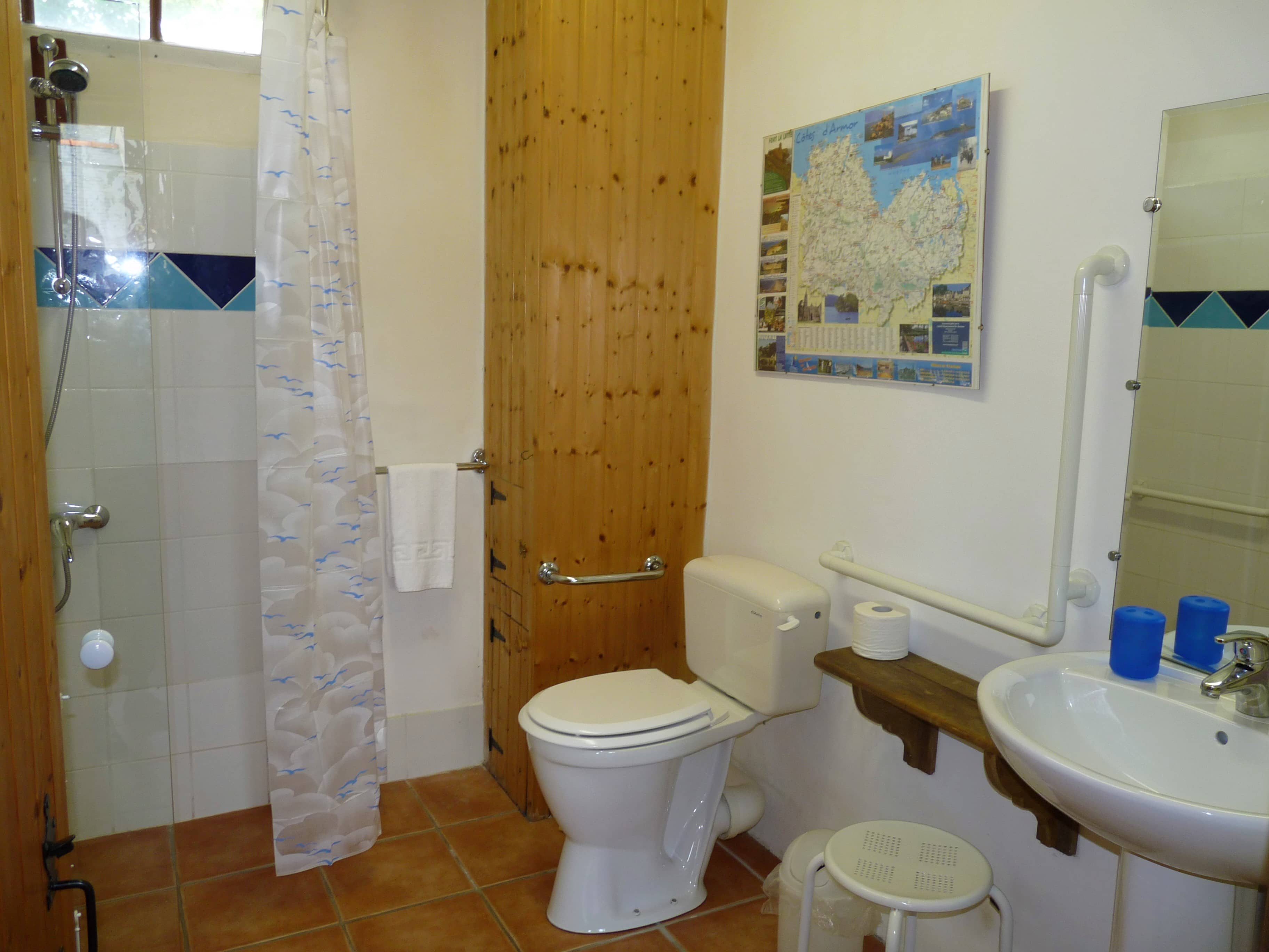 Clean and well-appointed toilet of La Julerie cottage in Brittany, France, with a ceramic sink, tiled walls, soft lighting, and modern decoration. Perfect for a comfortable and pleasant toilet experience.